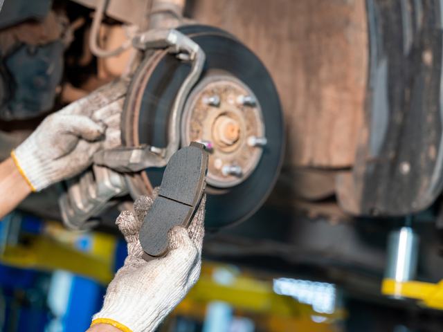 A mechanic fitting a new brake pad to a disc brake assembly